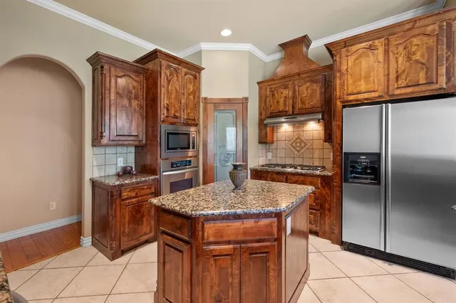a kitchen with stainless steel appliances granite countertop a refrigerator a stove and a sink