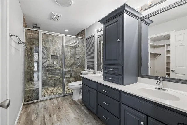 a bathroom with a double vanity sink toilet mirror and shower