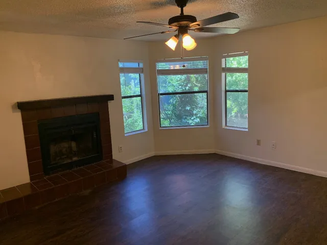 an empty room with wooden floor fireplace and windows