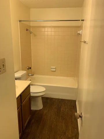 a bathroom with a granite countertop bathtub shower sink vanity and toilet