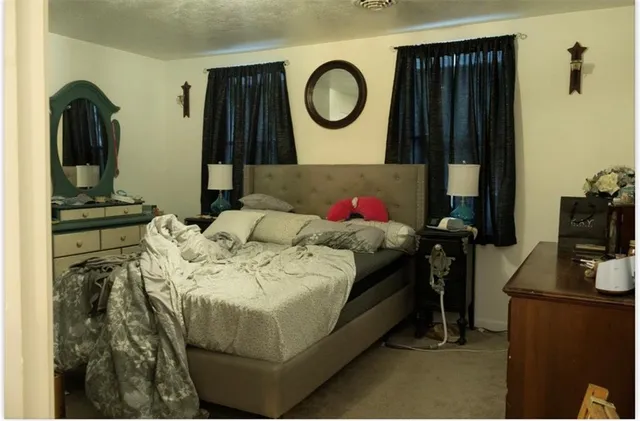 a bed sitting in a bedroom next to a window and dresser