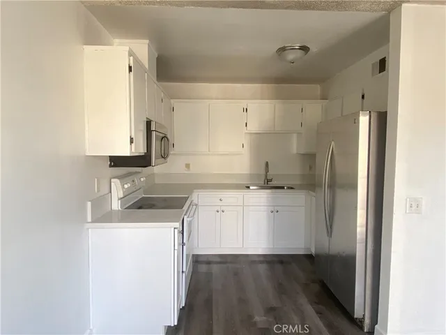 a kitchen with a sink cabinets stainless steel appliances and a refrigerator