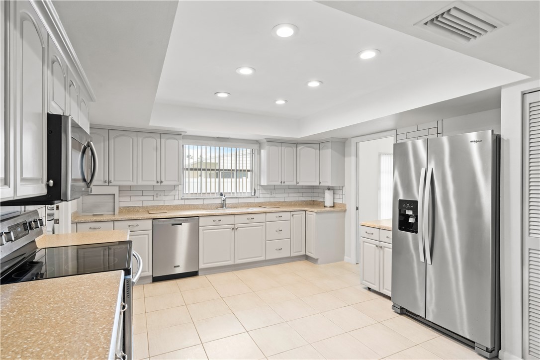 618 Conn Way Vero Beach, FL 32963 - Photo 7 of 36 a large white kitchen with a sink and dishwasher a refrigerator with white cabinets