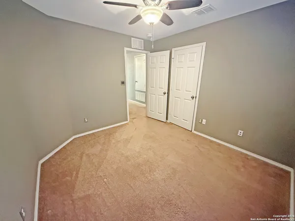 an empty room with chandelier fan and window