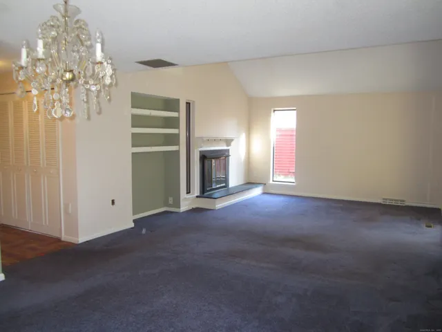 an empty room with a fireplace and chandelier fan