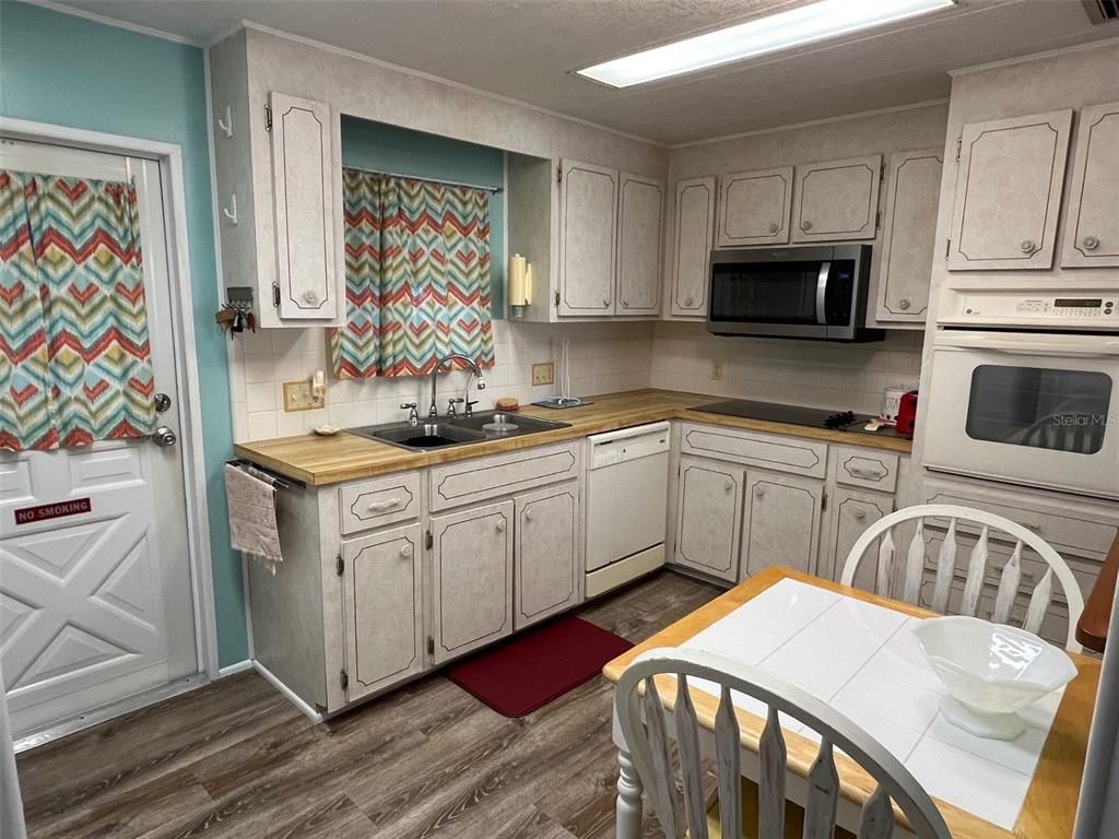 709 Sugar Palm Street Largo, FL 33778 - Photo 10 of 34 a kitchen with stainless steel appliances granite countertop a sink dishwasher a stove and white cabinets with wooden floor