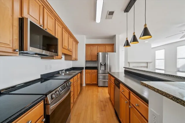 a kitchen with stainless steel appliances granite countertop a sink a stove and a refrigerator