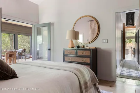 a bedroom with a bed a mirror and a large window with outer view