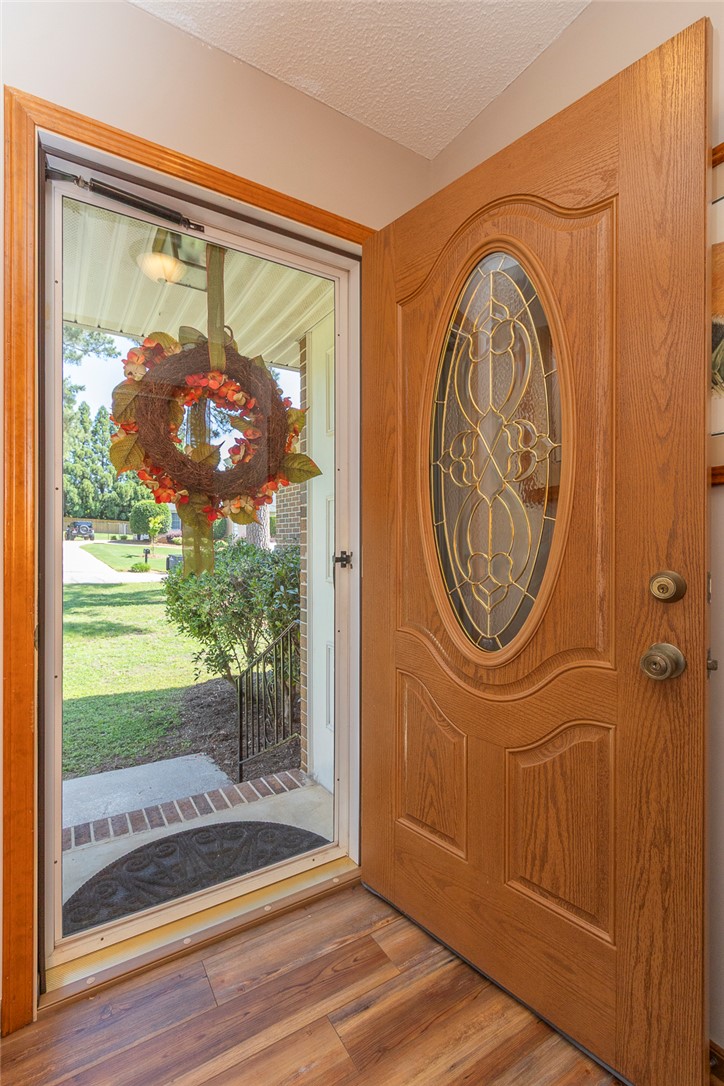 207 Laurel Ridge Road Anderson, SC 29621 - Photo 7 of 50 A welcoming front entrance features rich wood flooring and a decorative storm door, leading to a vibrant outdoor space.