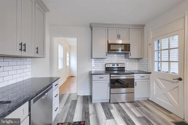 a kitchen with granite countertop a stove a sink and a microwave