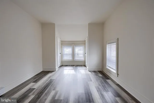 a view of an empty room with wooden floor and window