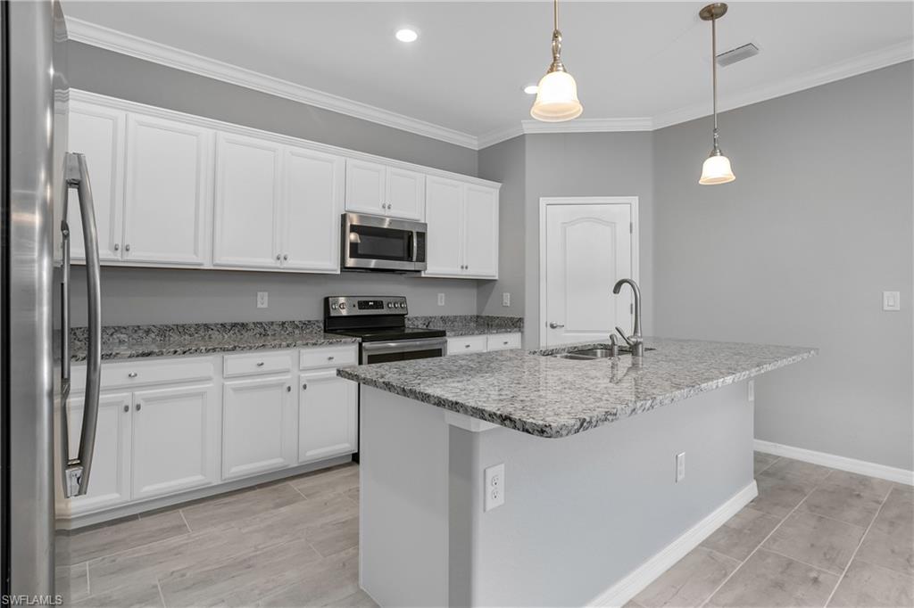 19952 Beverly Park Road Estero, FL 33928 - Photo 9 of 32 a kitchen with stainless steel appliances granite countertop a sink a stove top oven a counter space and cabinets