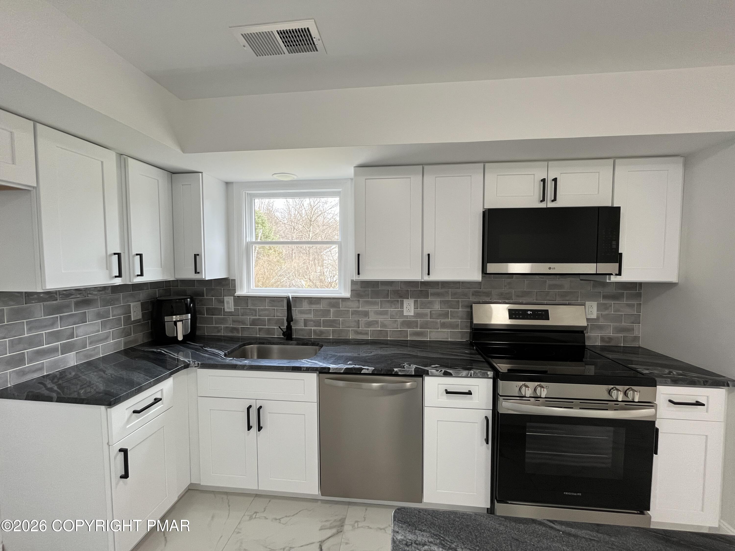 1281 Brian Lane Effort, PA 18330 - Photo 6 of 32 a kitchen with granite countertop white cabinets and black stainless steel appliances