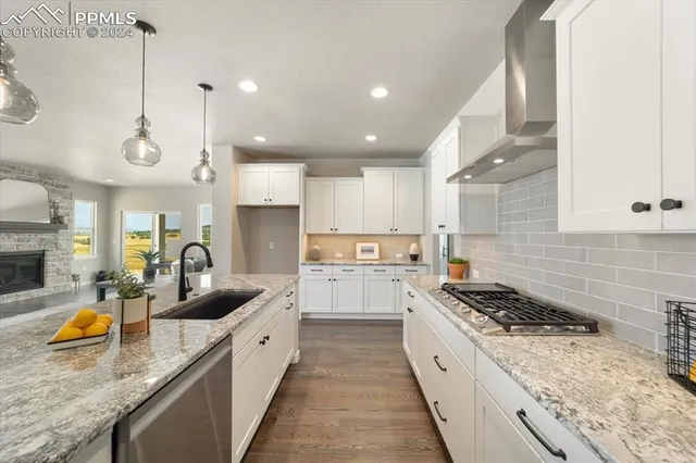 a large kitchen with stainless steel appliances granite countertop a sink a stove and a wooden floors