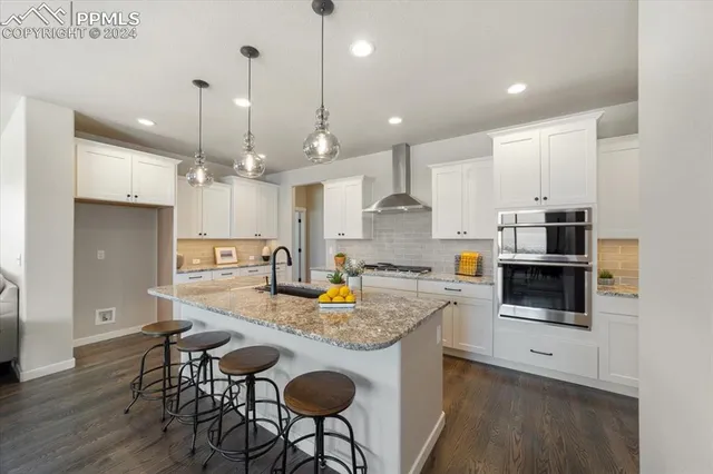 a kitchen with stainless steel appliances granite countertop a stove a kitchen island a refrigerator and a dining table with wooden floor