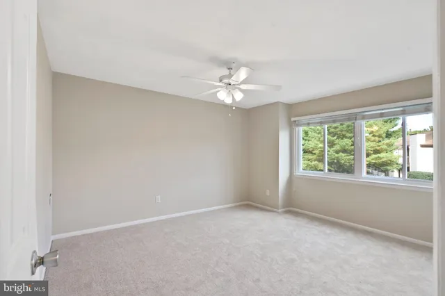 an empty room with a window and a ceiling fan