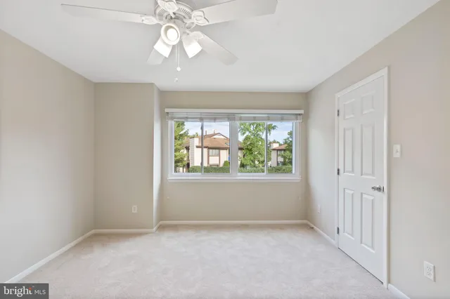 an empty room with windows and chandelier fan