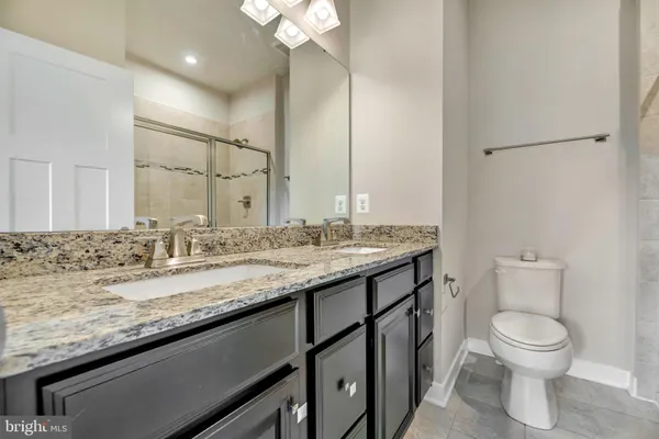 a bathroom with a granite countertop sink a toilet and a mirror