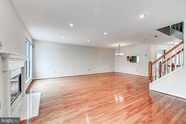 a view of an empty room with wooden floor and a kitchen