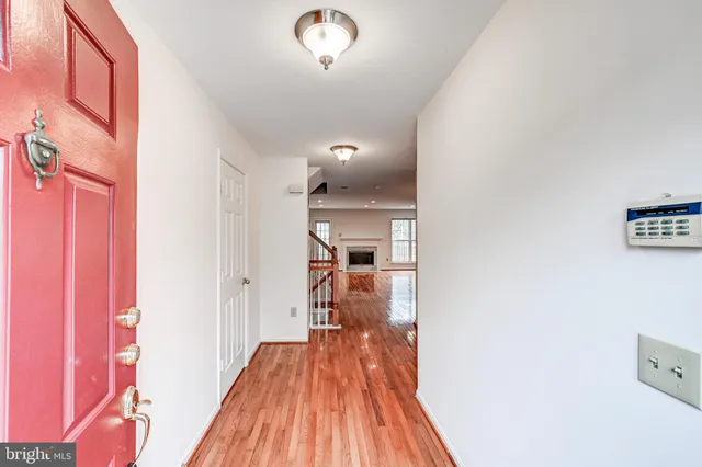 a view of a hallway with wooden floor and a bathroom