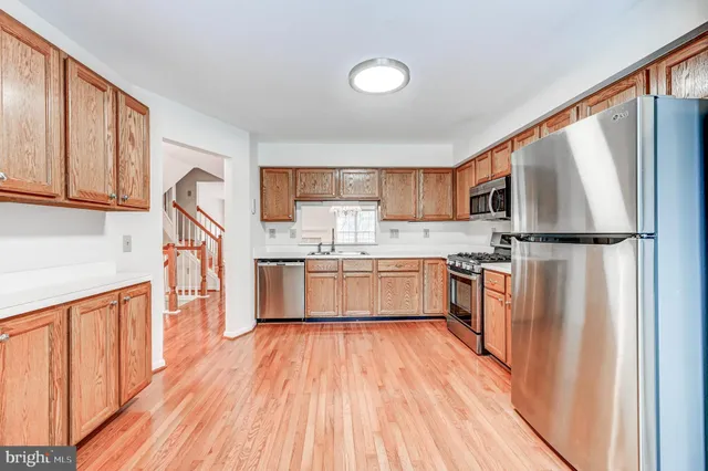 a kitchen with stainless steel appliances granite countertop a refrigerator a sink dishwasher and a stove with wooden floor