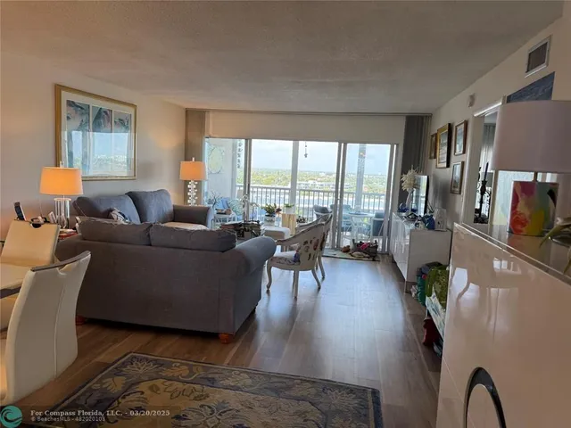 a living room with furniture floor to ceiling window and wooden floor