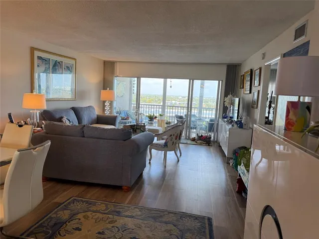 a living room with furniture floor to ceiling window and wooden floor
