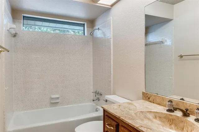 a bathroom with a granite countertop sink a mirror and a bathtub