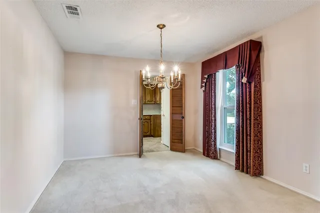 an empty room with chandelier fan and windows