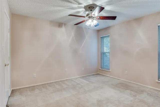 an empty room with a chandelier fan and wooden floor