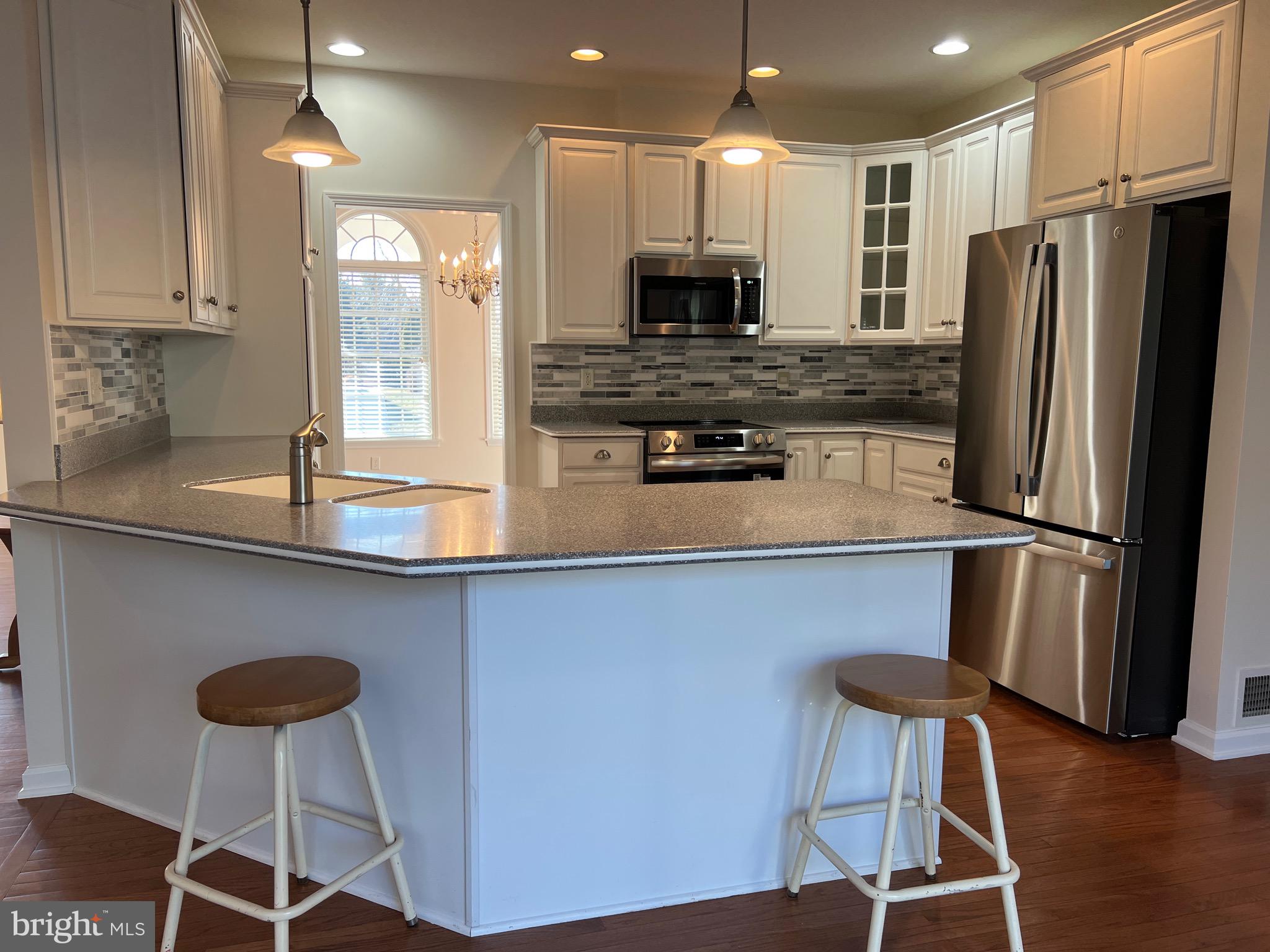 6337 Medina Ridge Drive Fayetteville, PA 17222 - Photo 20 of 50 a kitchen with stainless steel appliances granite countertop a refrigerator a stove a sink counter and chairs with wooden floor