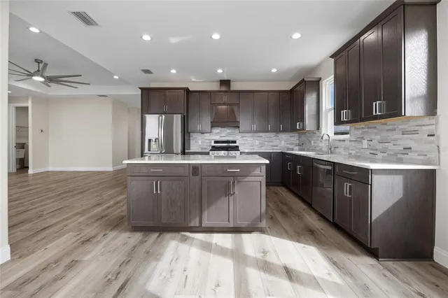 a large kitchen with stainless steel appliances granite countertop a sink a stove and a refrigerator