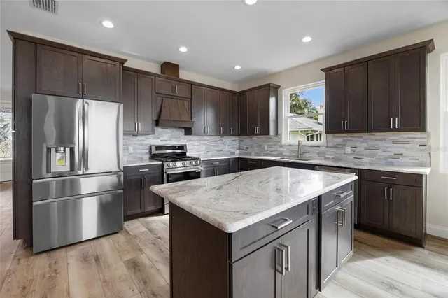 a kitchen with kitchen island granite countertop a sink stove and refrigerator