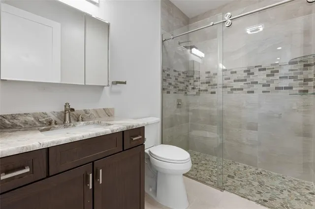 a bathroom with a granite countertop sink a toilet and shower