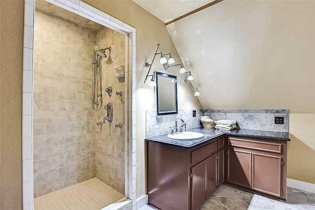 a bathroom with a granite countertop sink a mirror and shower