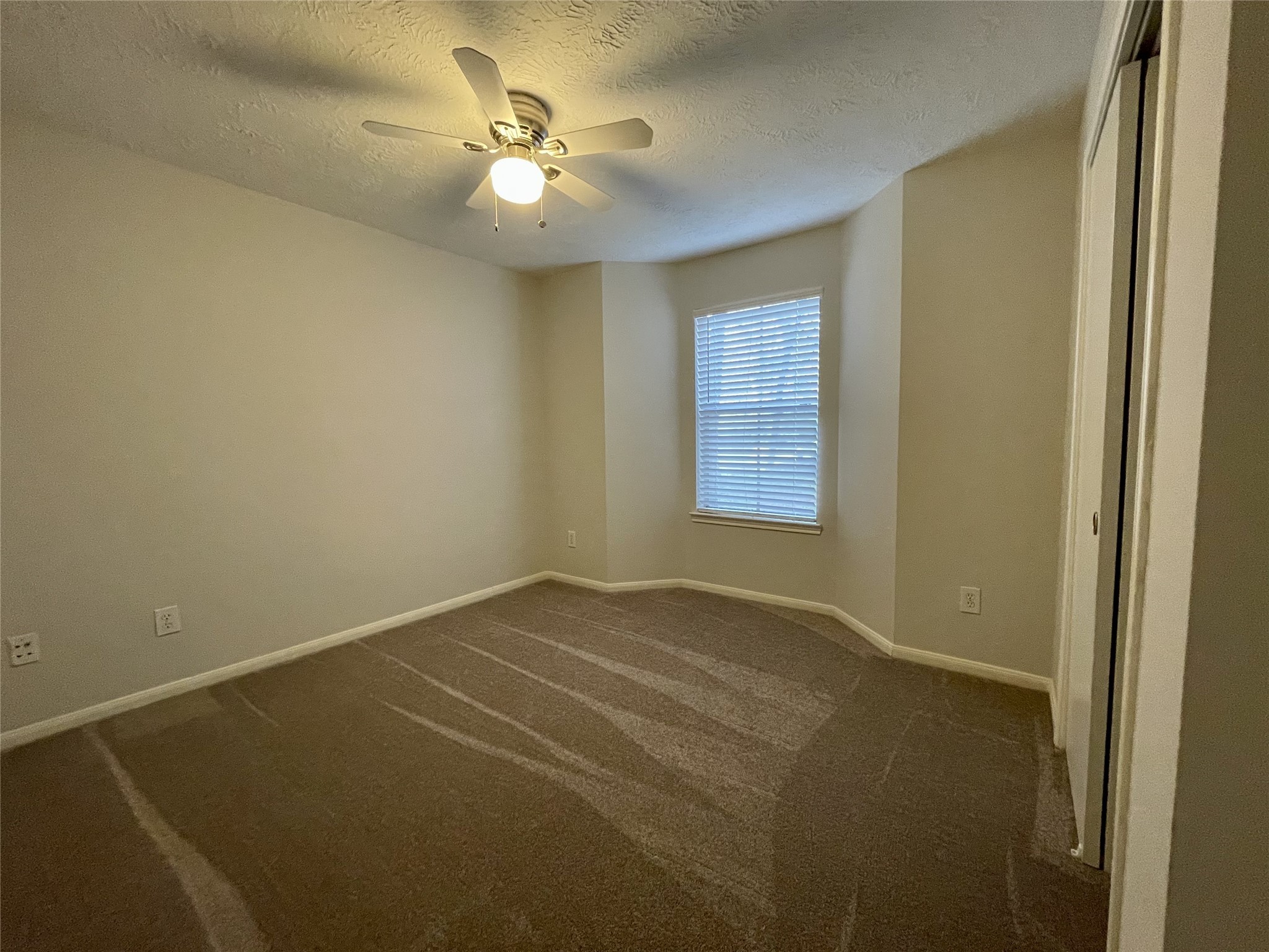 8051 Bay Branch Drive, Unit 312 The Woodlands, TX 77382 - Photo 12 of 22 an empty room with a chandelier fan and windows