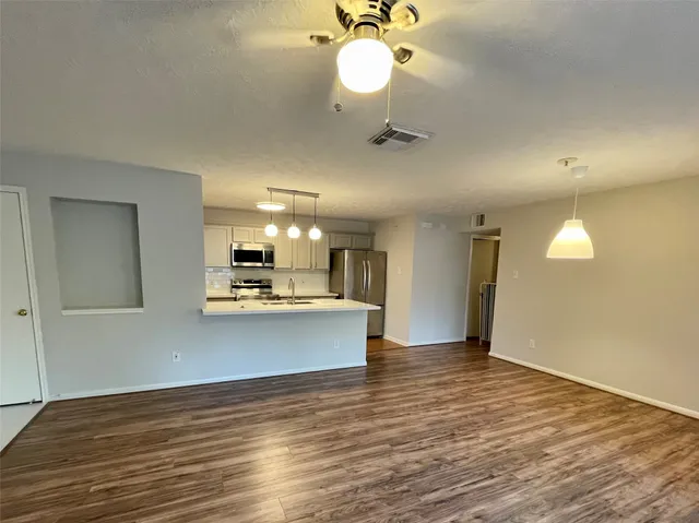 a view of a kitchen with wooden floor and a ceiling fan