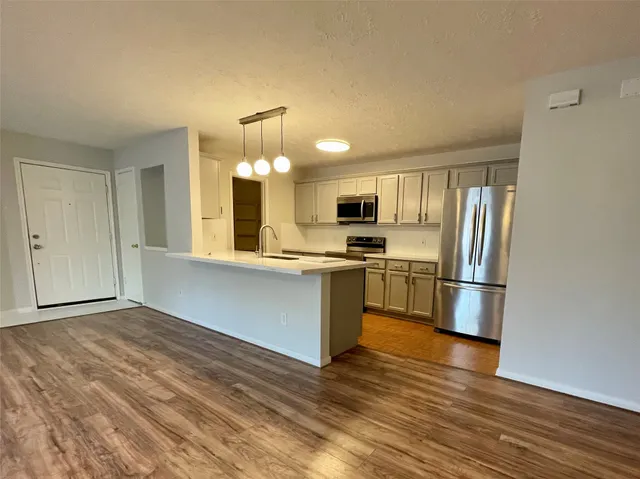 a kitchen with granite countertop a refrigerator and a stove top oven
