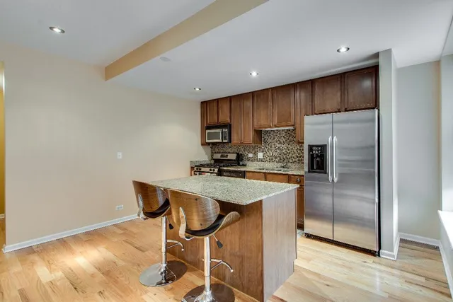 a kitchen with granite countertop a table chairs refrigerator and microwave