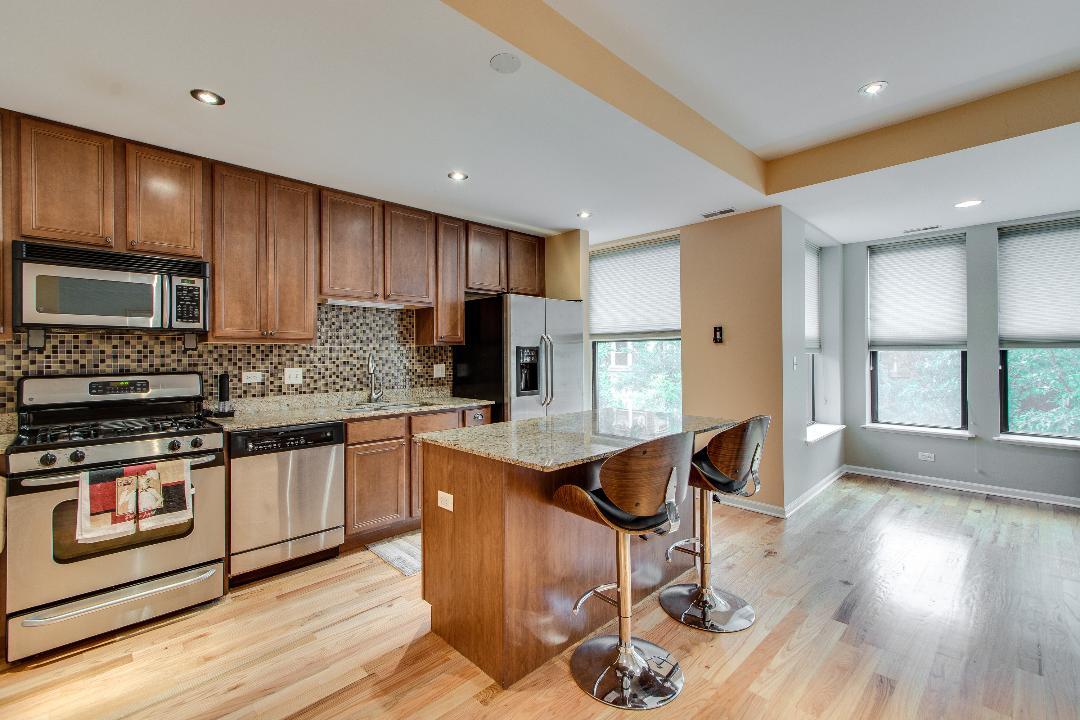 4740 South Ingleside Avenue, Unit 2N Chicago, IL 60615 - Photo 6 of 12 a kitchen with stainless steel appliances granite countertop wooden cabinets a stove a sink and a refrigerator