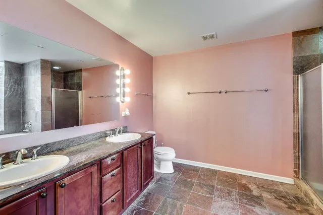 a bathroom with a granite countertop sink a toilet a mirror and shower