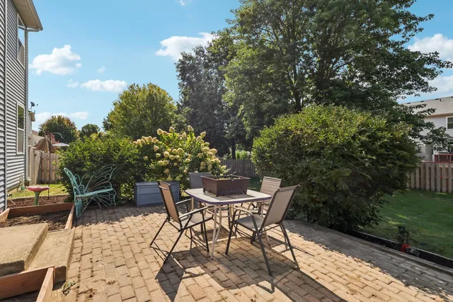 a patio with table and chairs and potted plants
