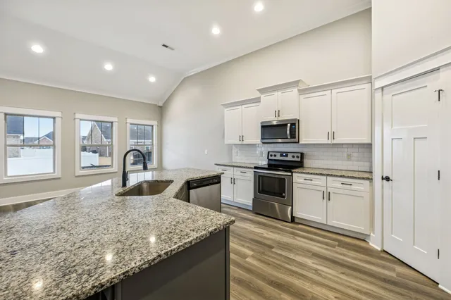 a kitchen with granite countertop a sink stove and refrigerator