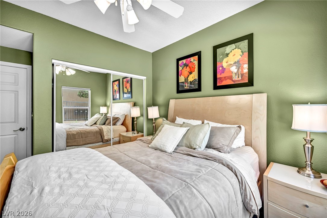 10730 Amber Ridge Drive, Unit 101 Las Vegas, NV 89144 - Photo 16 of 32 Comfortable bedroom featuring ample natural light, a ceiling fan, and sliding closet doors for convenient access.