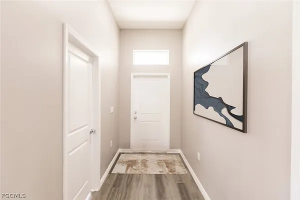 a view of a hallway with wooden floor and a bathroom