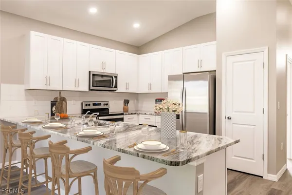 a kitchen with stainless steel appliances granite countertop a sink a stove a microwave a refrigerator and cabinets