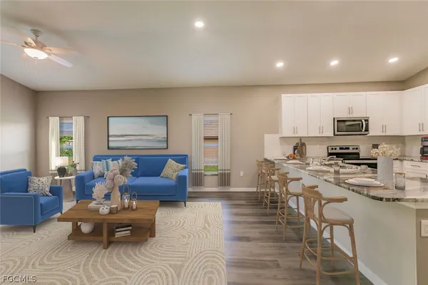 a living room with stainless steel appliances furniture a couch and a window