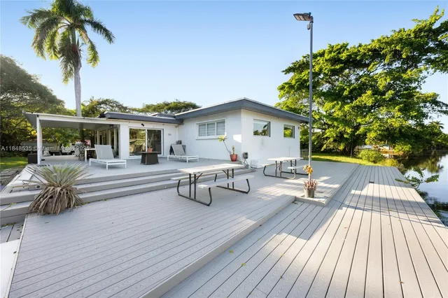 a view of a patio with table and chairs potted plants with wooden floor and fence