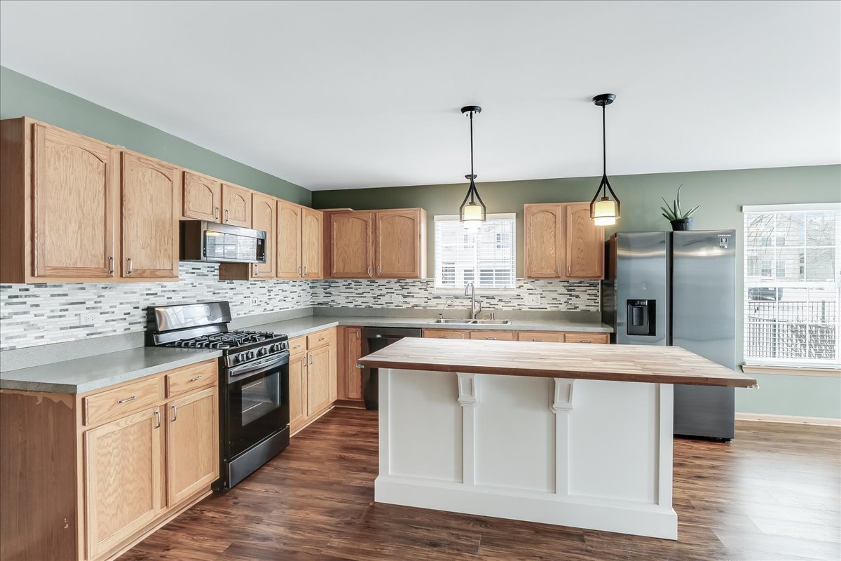 600 Spring Drive Marengo, IL 60152 - Photo 4 of 28 a kitchen with stainless steel appliances granite countertop a stove a sink dishwasher a refrigerator and white cabinets with wooden floor