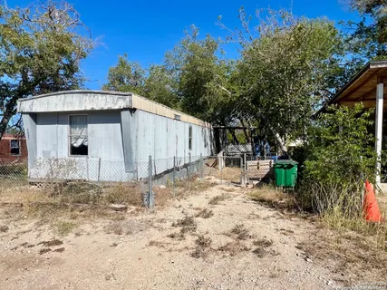 a backyard of a house with table and chairs under an umbrella